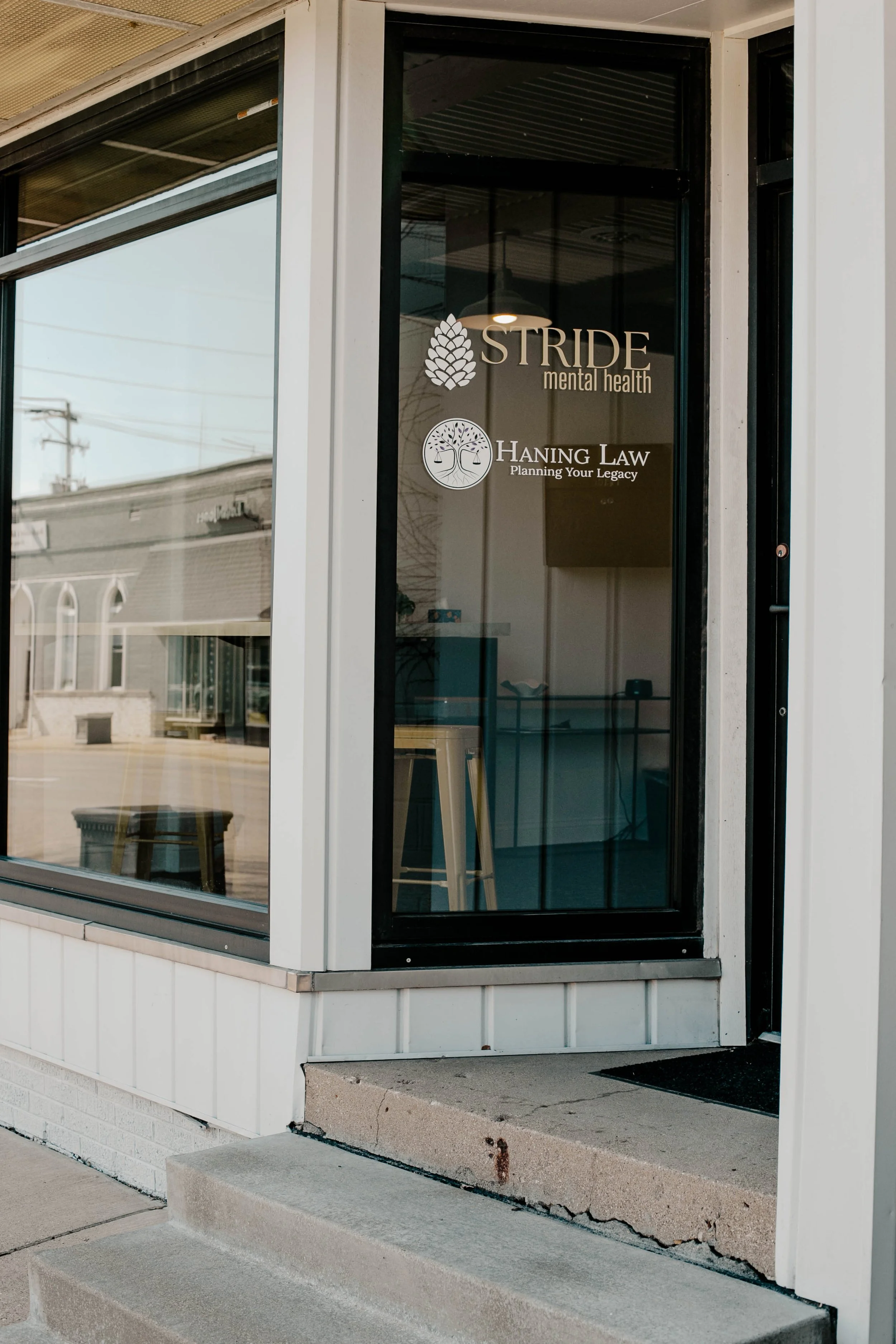 The glass door of a mental health office with the names and logos of Stride Mental Health and Haning Law printed on it.