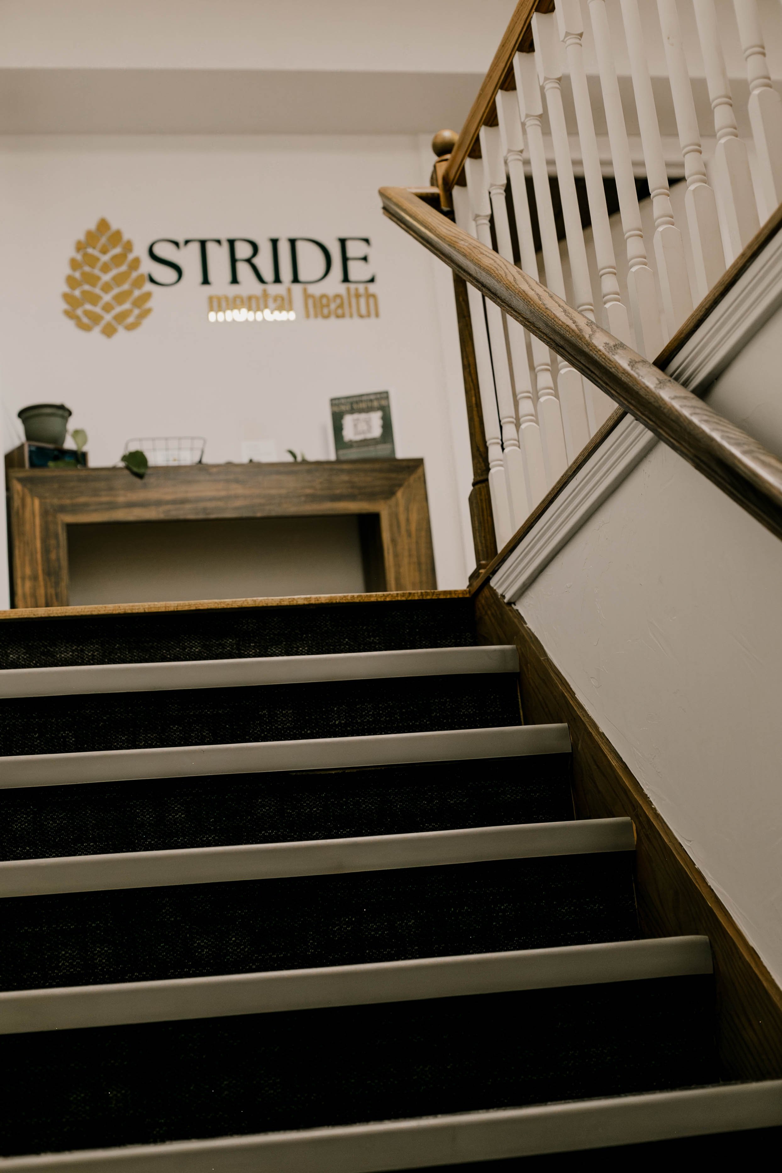 Staircase leading to a medical office with a sign on the wall that reads 'STRIDE mental health' with a pine cone graphic next to the text.