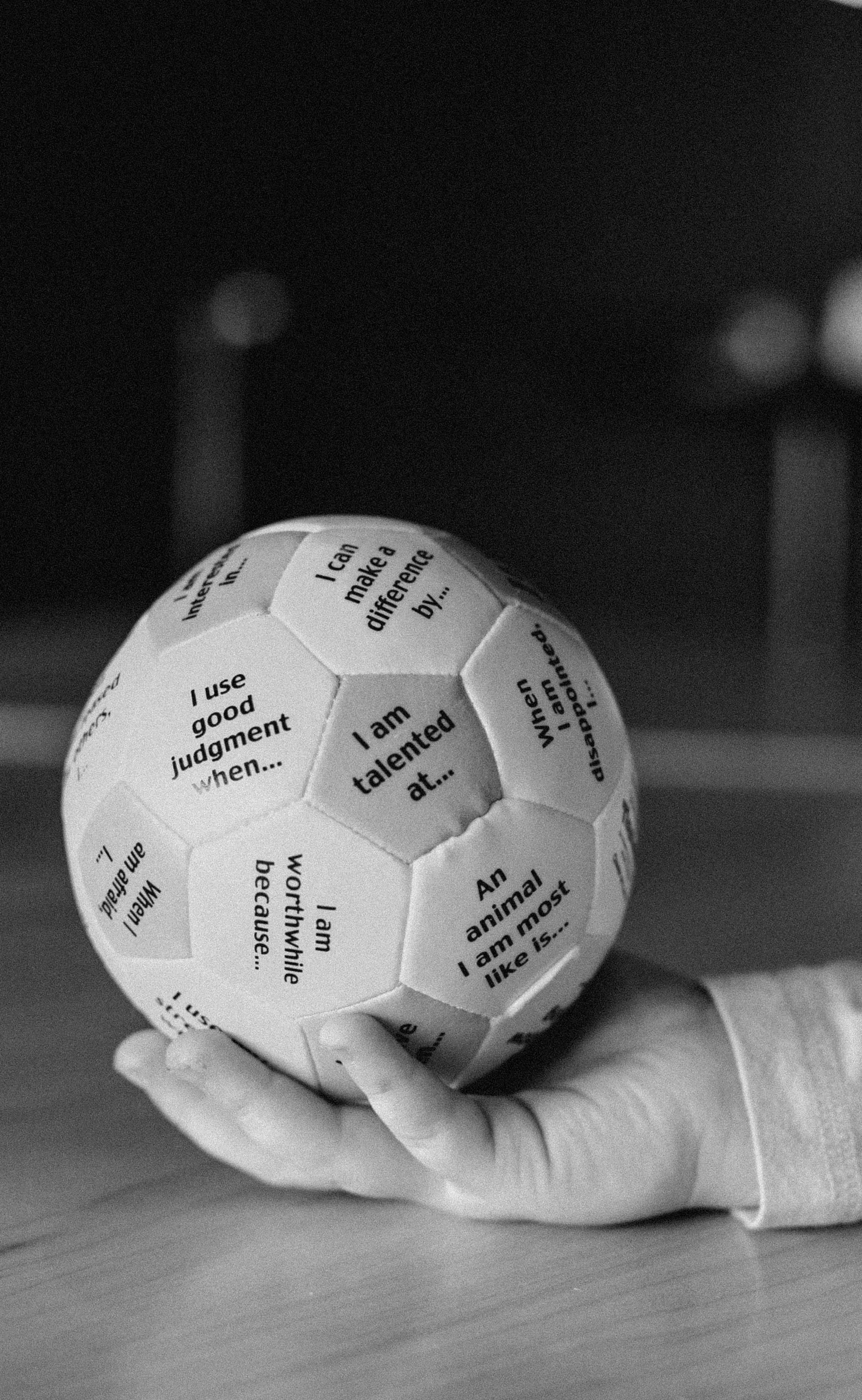 A hand holding a spherical object made of hexagon-shaped pieces with positive affirmations and statements about talents and judgments.