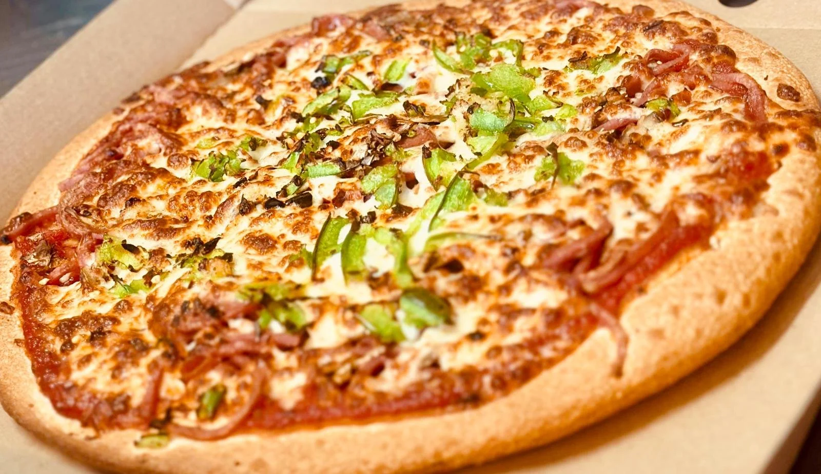 Jessie's Pizza An oval pizza topped with green bell peppers, black olives, onions, cheese, and sliced pepperoni in a cardboard pizza box. best pizza in Point Cook