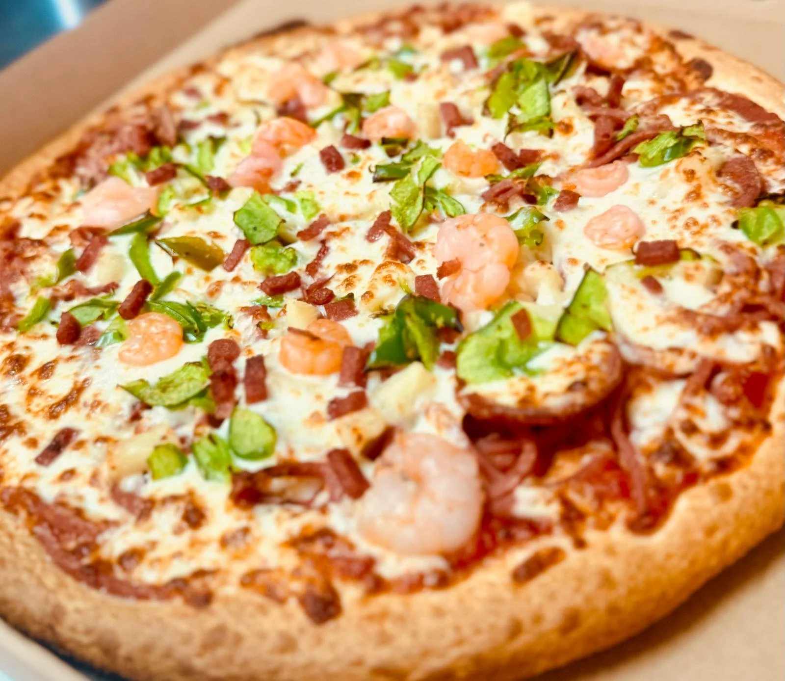 Jessie's Pizza Close-up of a seafood pizza with cheese, shrimp, bacon, green peppers, and other toppings on a crust. best pizza in Point Cook