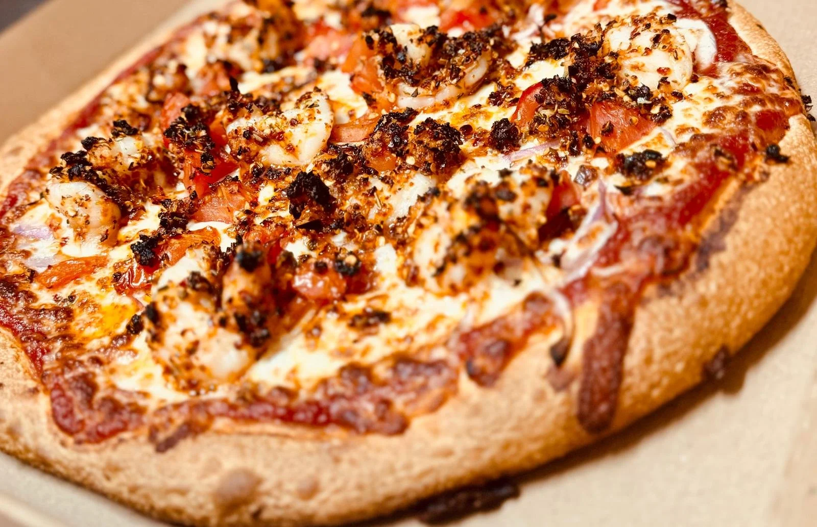 Jessie's Pizza Close-up of a pizza with cheese, tomato, and bacon, topped with spicy seasoning. best pizza in Point Cook