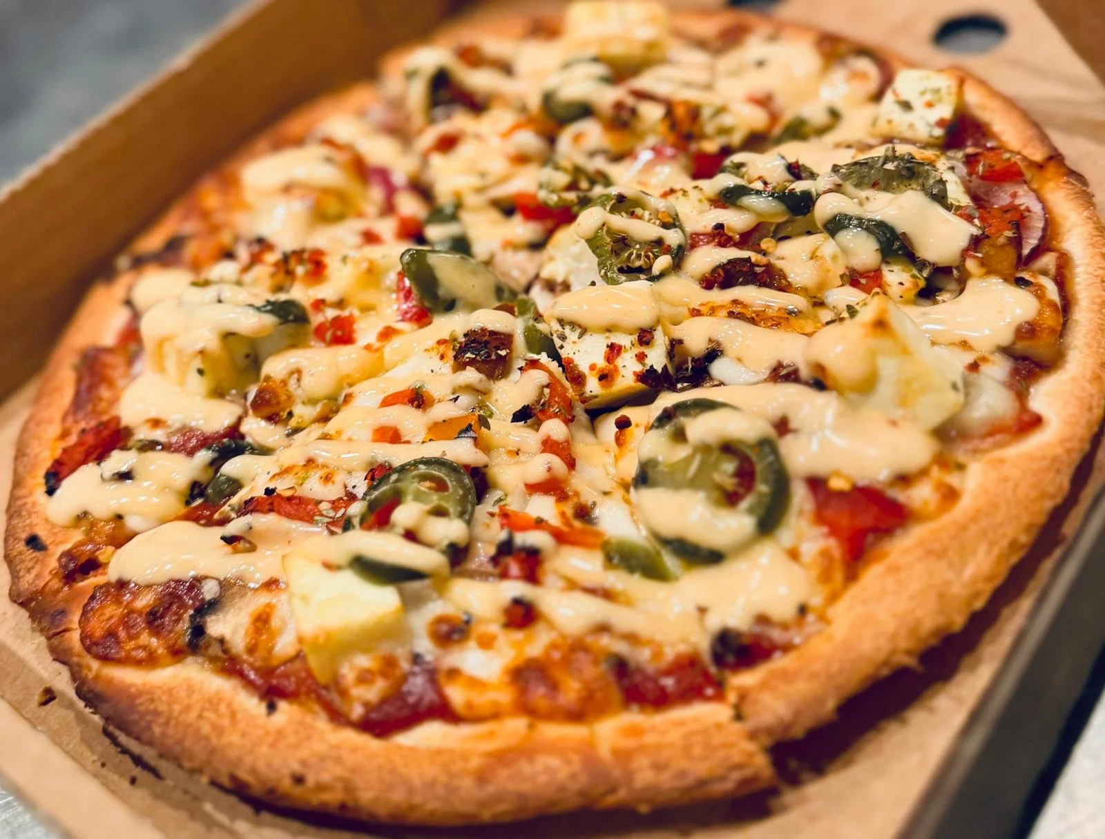 Jessie's Pizza Close-up of a pizza with cheese, jalapenos, and cooked vegetables best pizza in Point Cook