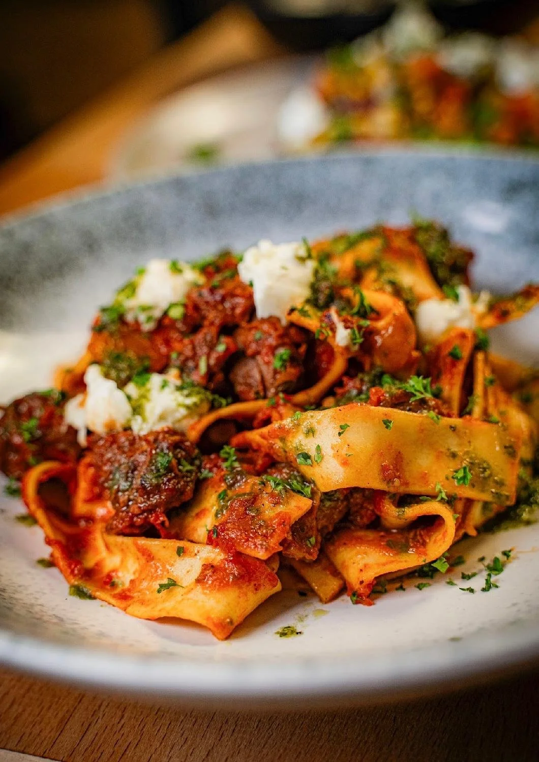 A plate of Ragu Napoletano with a rich braised lamb ragu, Italian tomatoes, fresh herbs, pesto and straciatello.