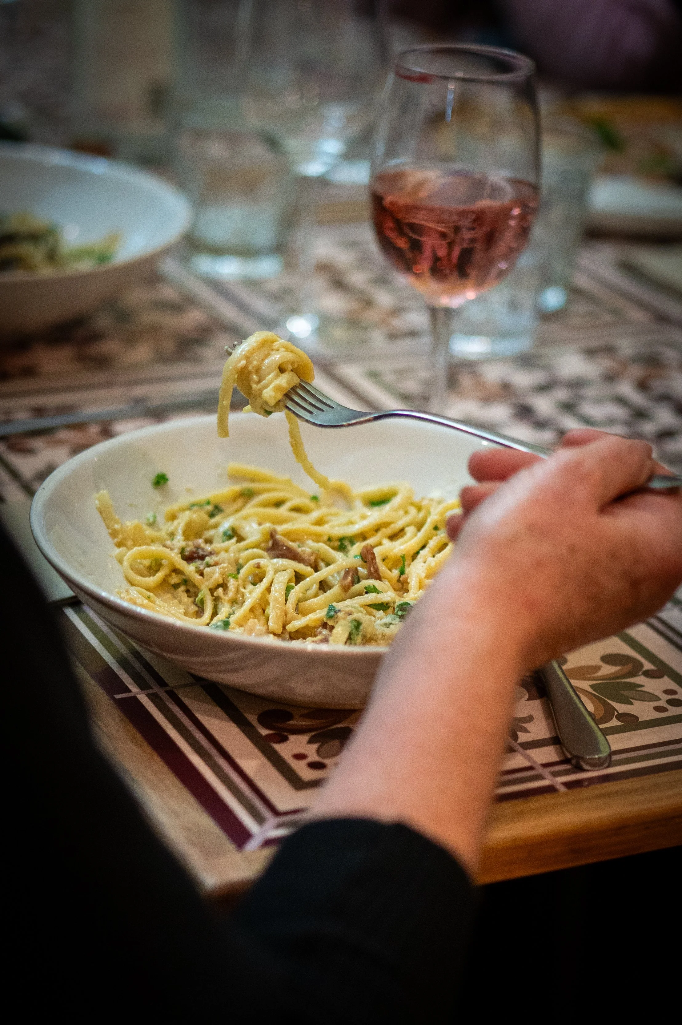 Creamy carbonara pasta twirled on a fork with crispy guanciale, pecorino romano, and black pepper.
