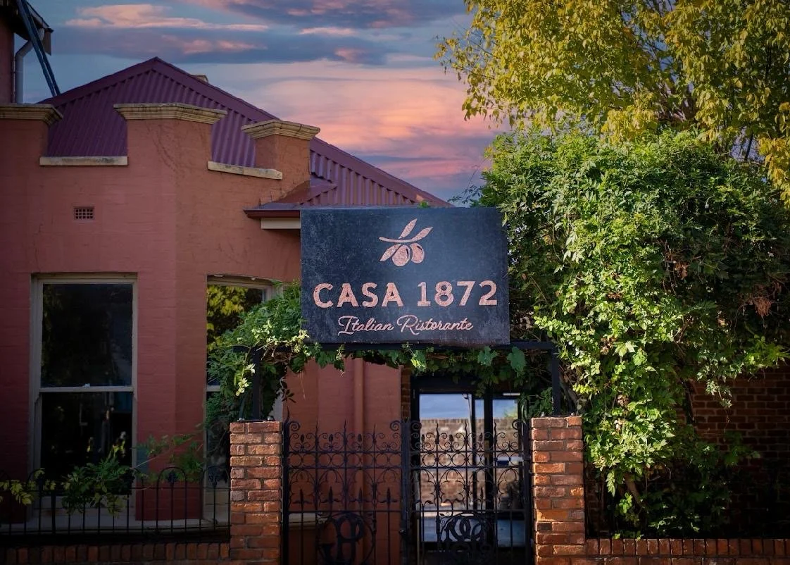 Illuminated exterior sign above the High Street entrance to Casa 1872 Italian Ristorante at twilight.