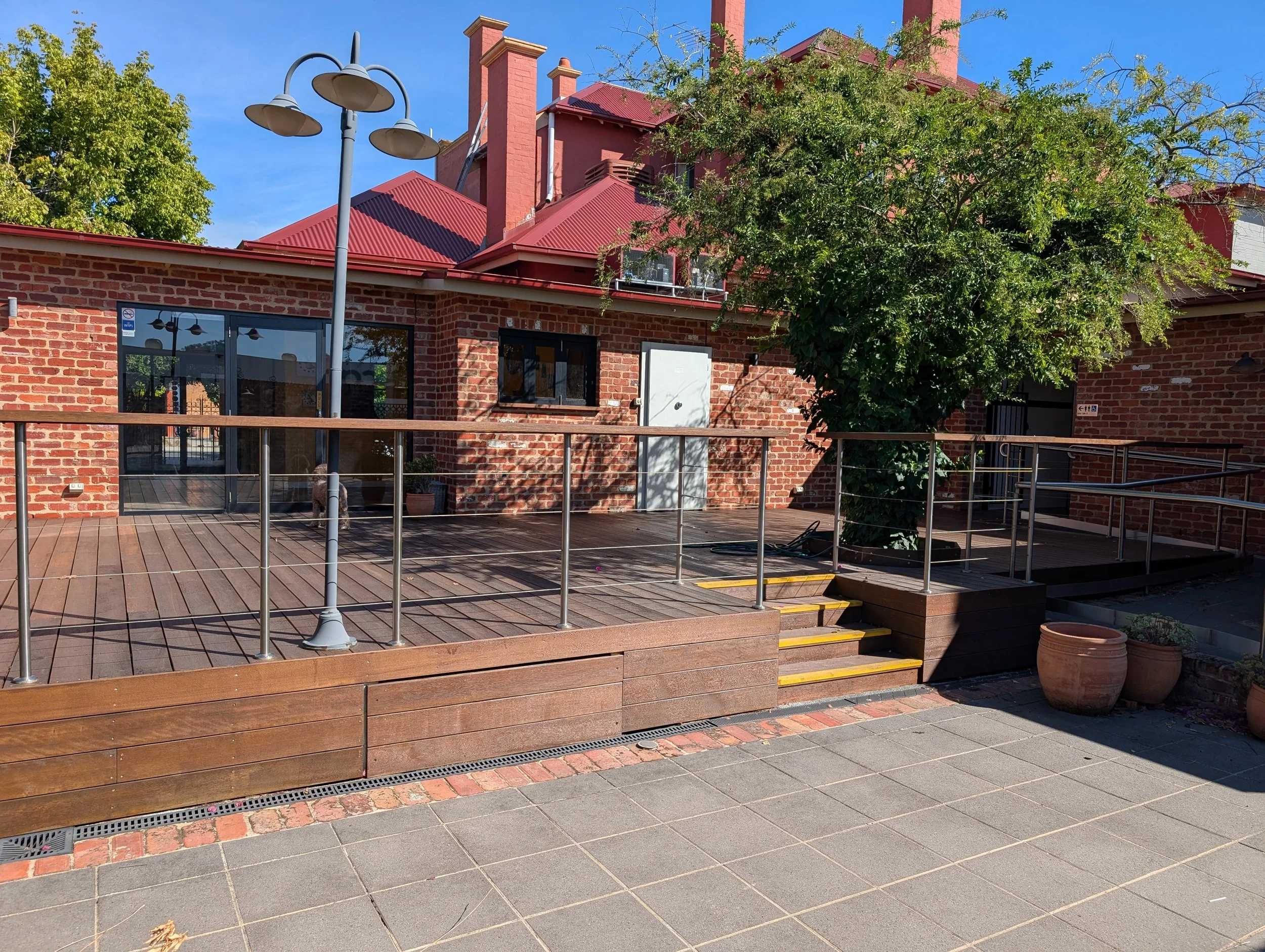 Daytime view of the back courtyard and patio dining area, with access via a ramp or stairs..