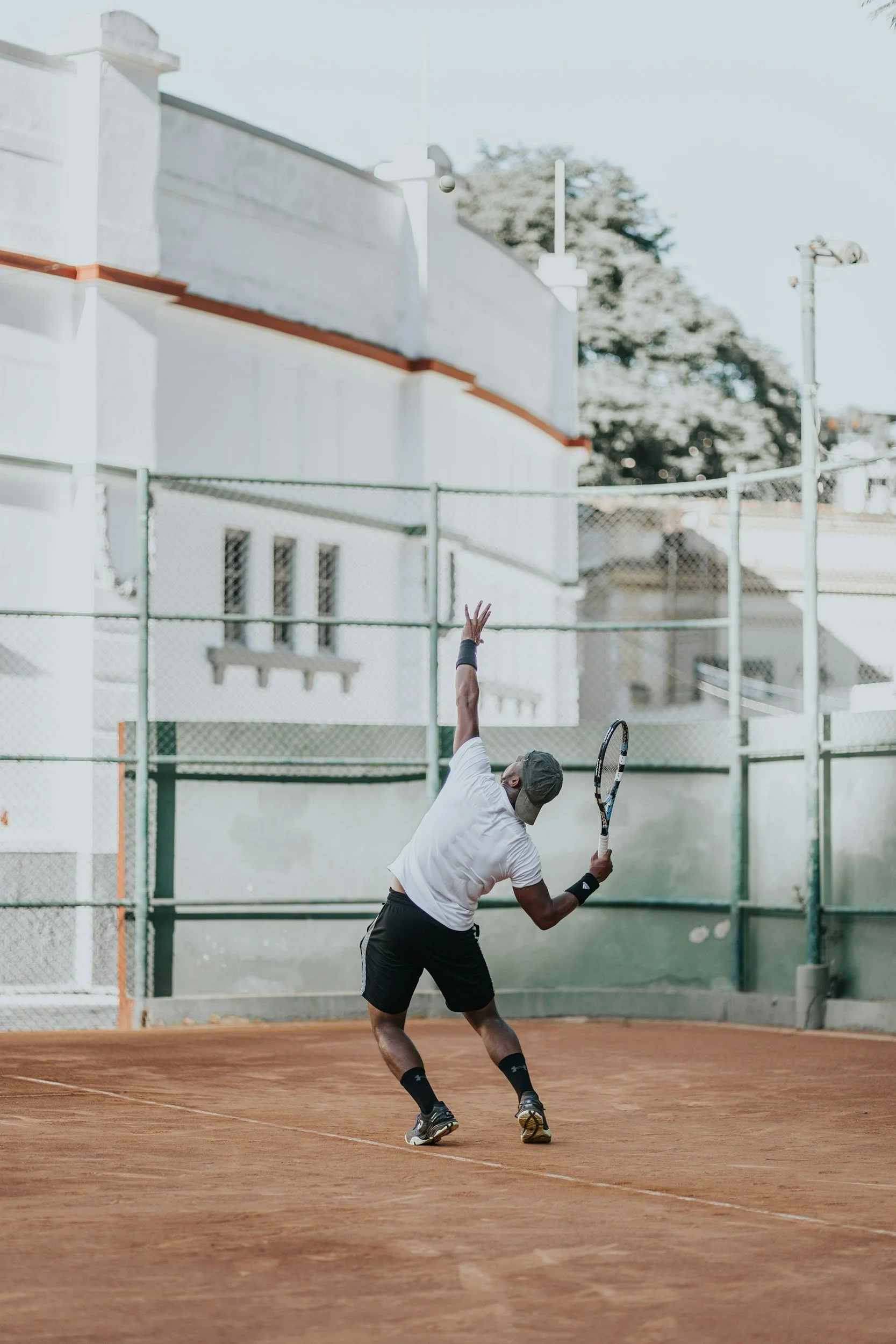 A man playing tennis on a clay court with a tennis racket, preparing to hit the ball