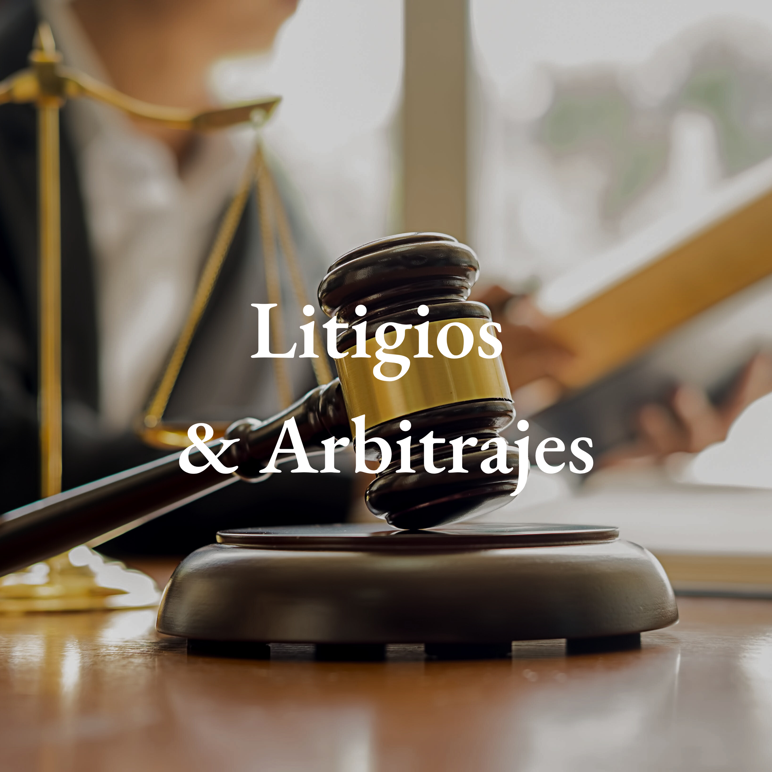 Martillo de juez y balanza sobre una mesa, con una persona en el fondo leyendo un libro, representando temas de litigios y arbitrajes.