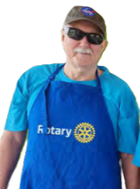 Older man wearing sunglasses, a hat, a blue Rotary apron, and a blue shirt.