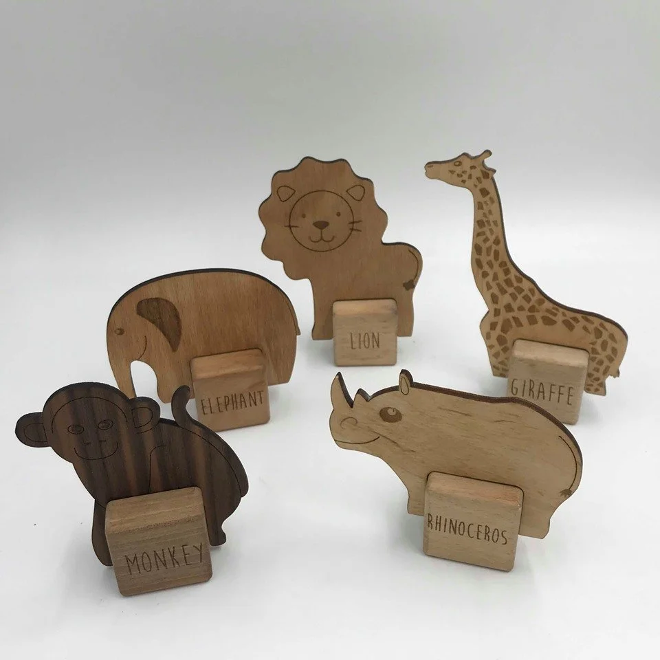 Wooden animal figurines of a monkey, elephant, lion, giraffe, and rhinoceros on white background.