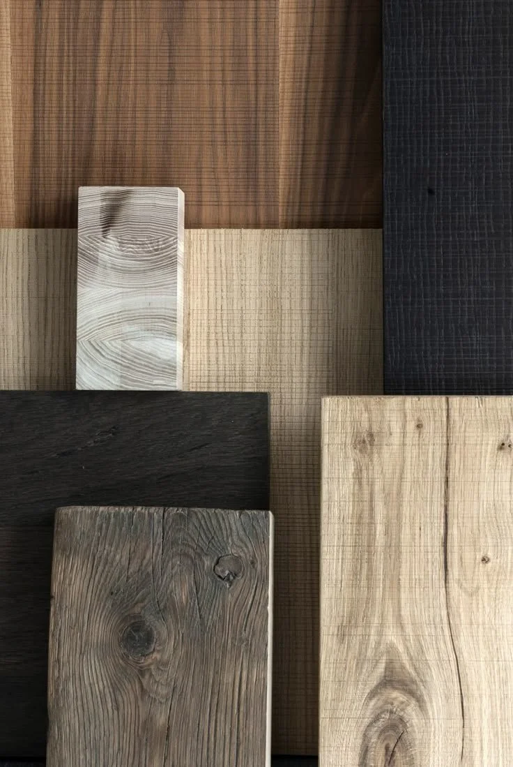 Collection of wooden planks in various colors and wood grains arranged on a wall.