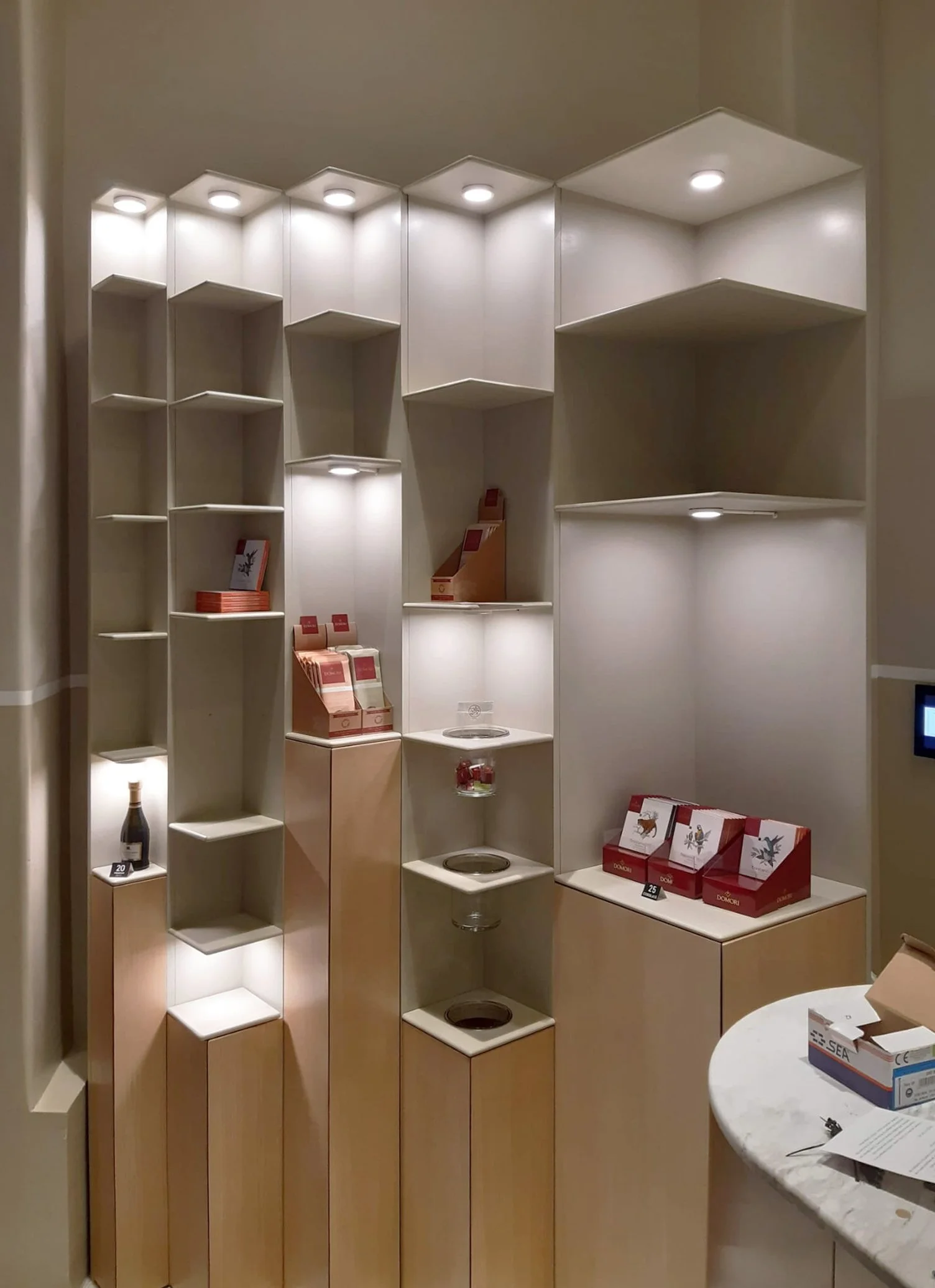 Empty display shelves with built-in lighting, a few boxed products, and some cooking pots in a retail store setting.