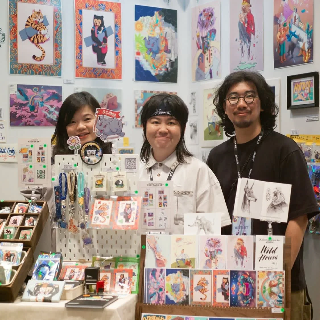 Malaysia Artist OCMay at her booth during Bangkok Illustration Fair 2025, with a curated display of nature-inspired illustrations and art merchandise.