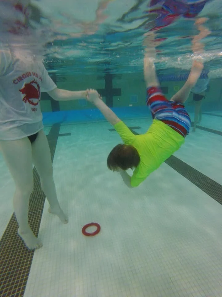 SWAM swimmer diving for a sinky toy underwater, holding his instructors hand