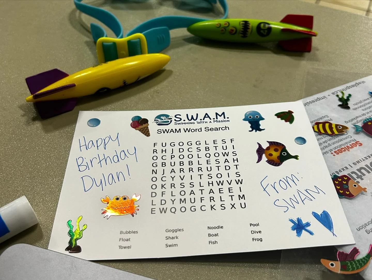 a swimming-themed word search puzzle with the message "Happy Birthday Dylan!" handwritten in blue marker