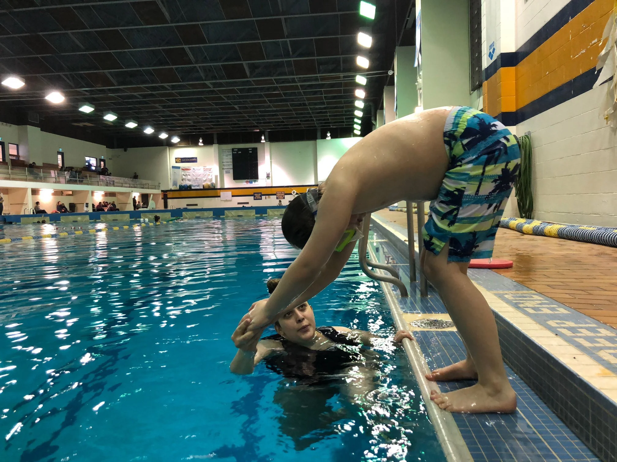 SWAM instructor assisting a swimmer with learning how to dive in the deep end