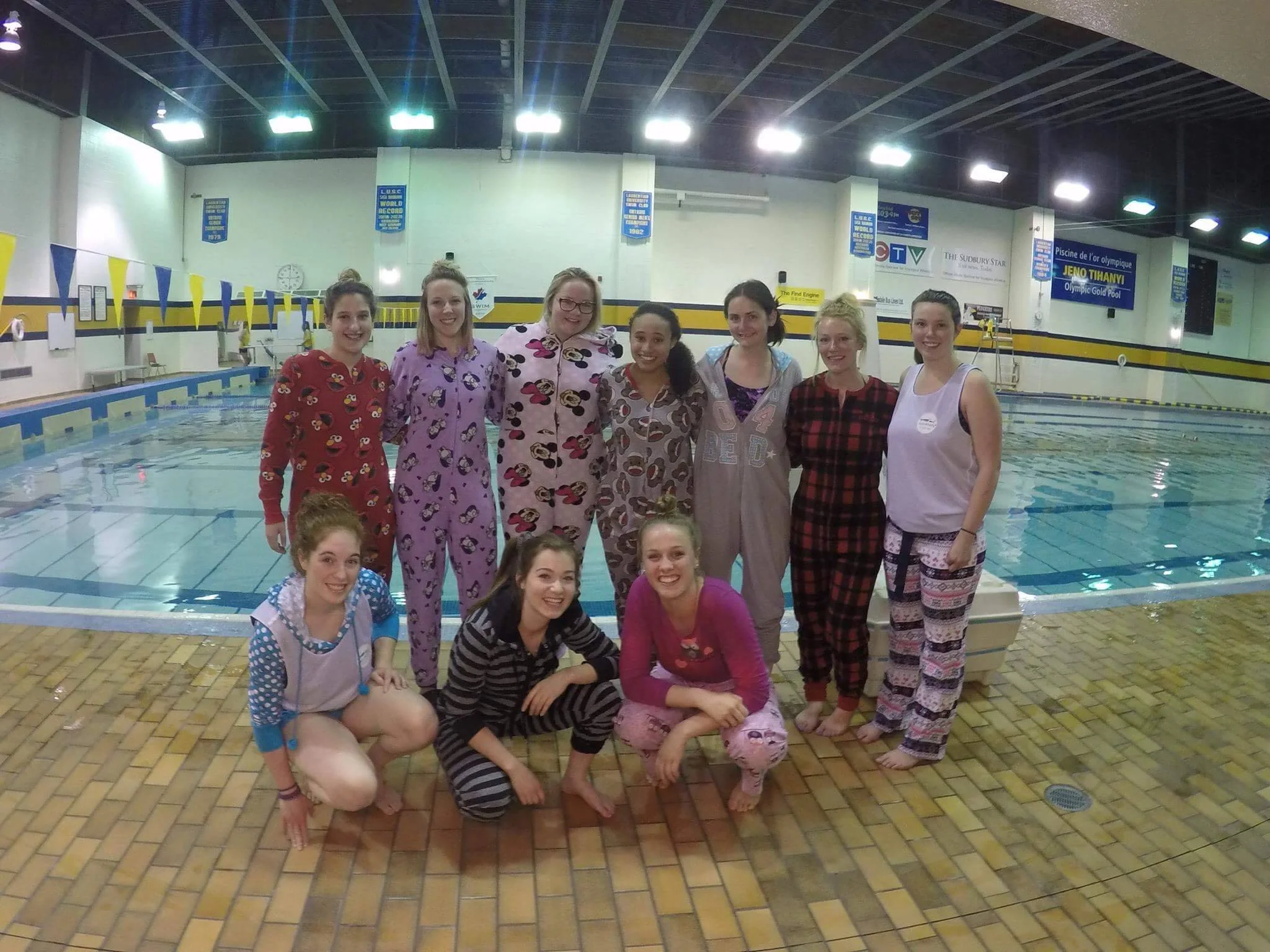volunteers wearing pajamas smiling on pool deck