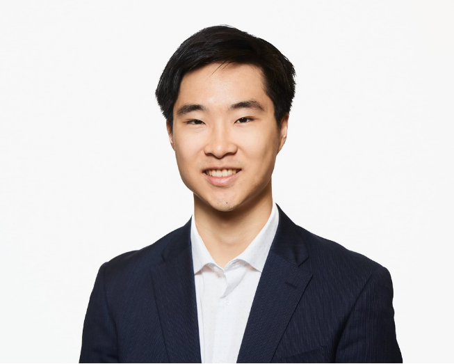 David Jin smiling in front of a white wall 