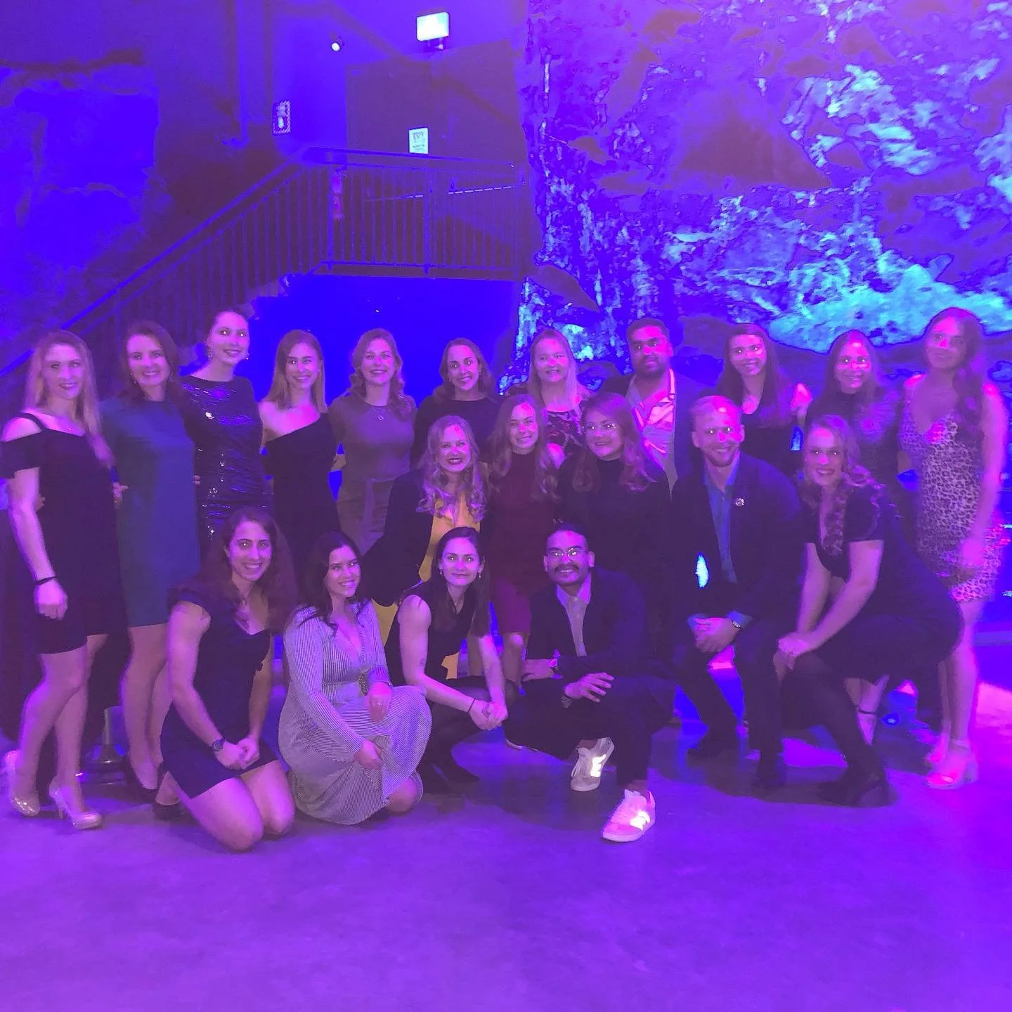 group of SWAM volunteers posing for a photo at a social event with a blue-lit rocky background