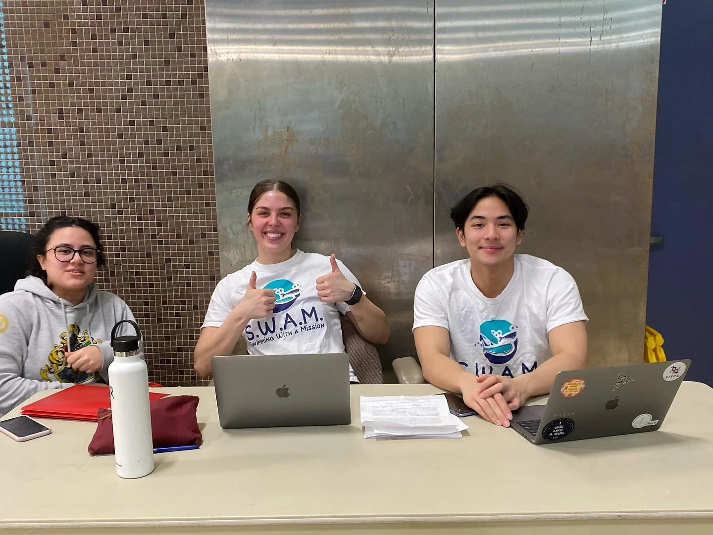 three SWAM Montreal volunteers sitting at a table and smiling
