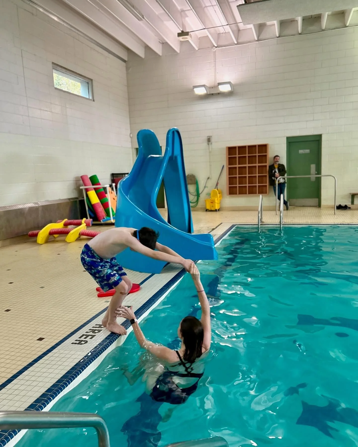 instructor helping swimmer do a dive from the edge of the pool