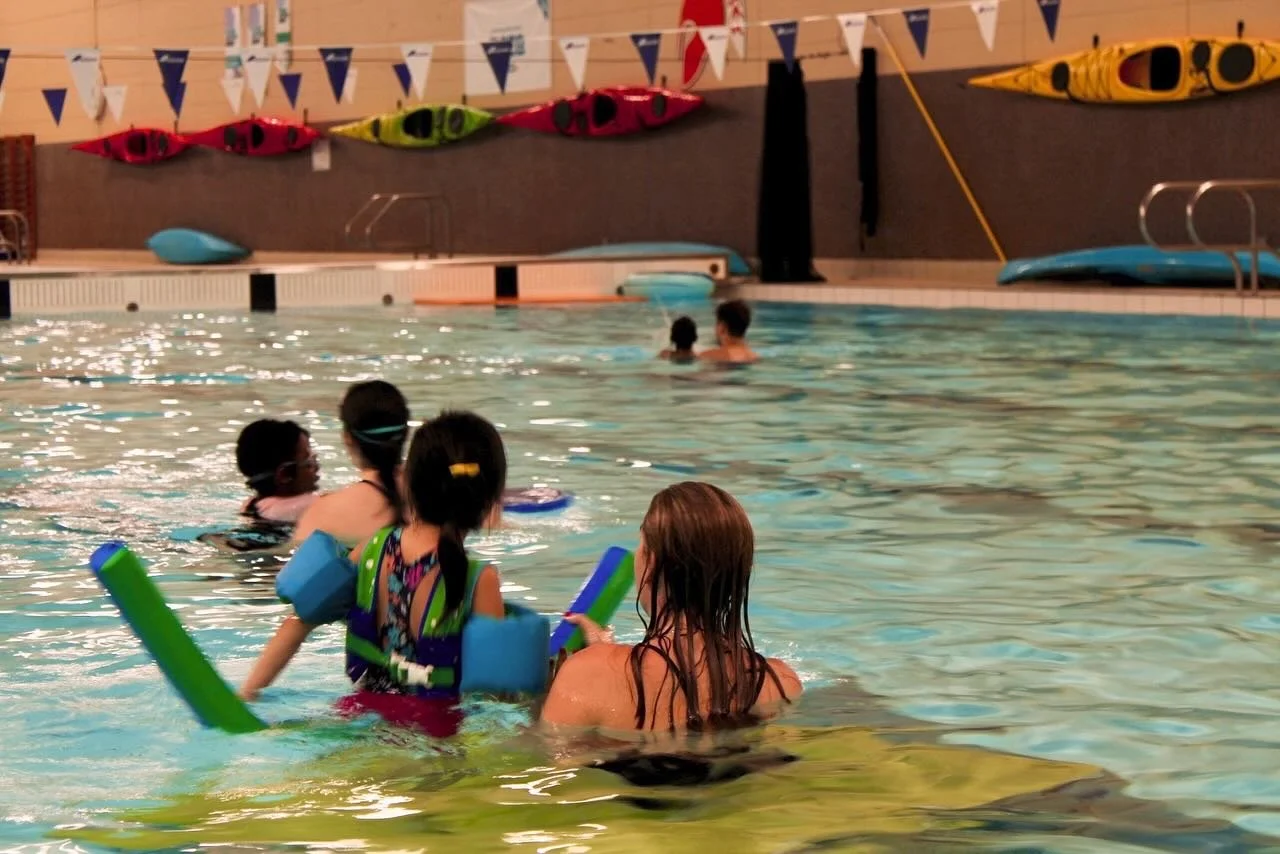 swimmer-instructor pairs looking away from the camera, in pool