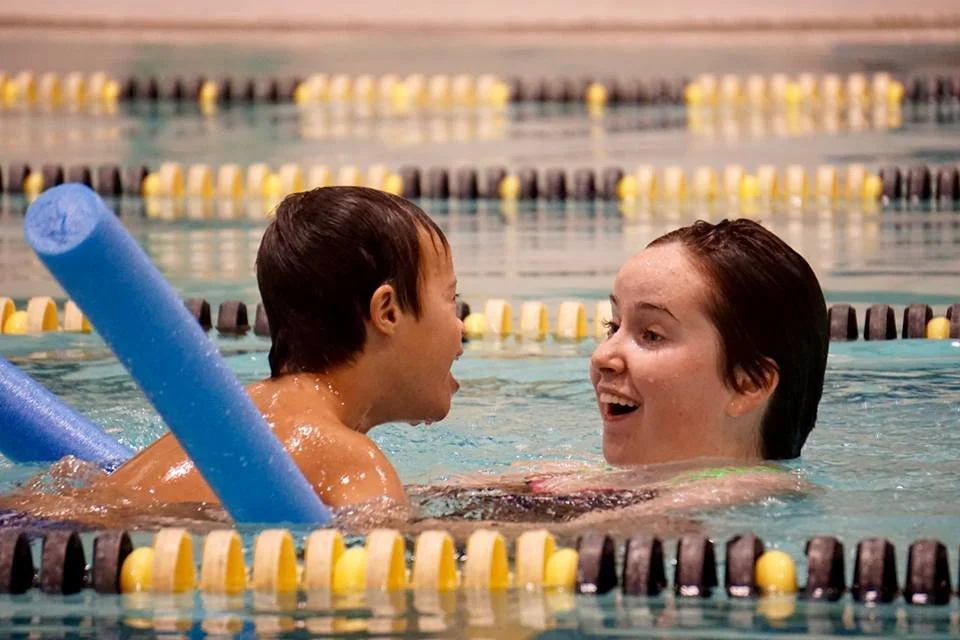 swimmer and instructor smiling at each other