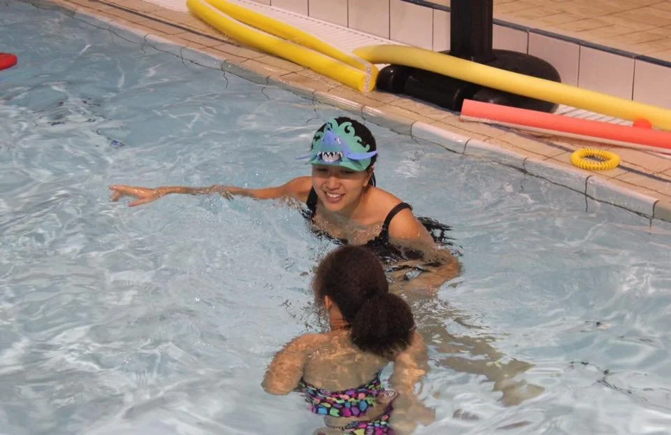 instructor with funny hat smiling at swimmer