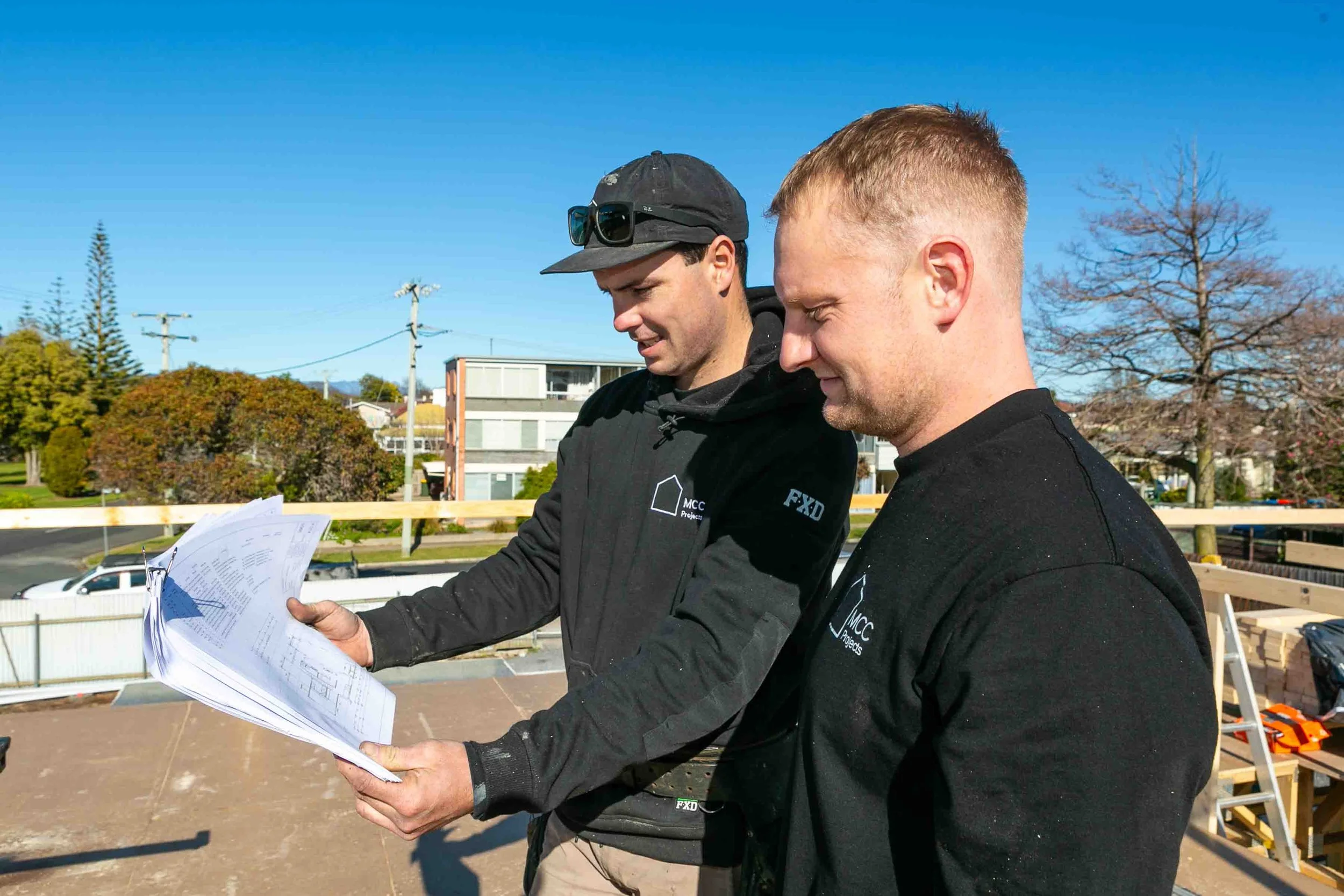 Builders working together on a roof, reviewing the plans for a townhouse in Devonport as part of the MCC projects team.