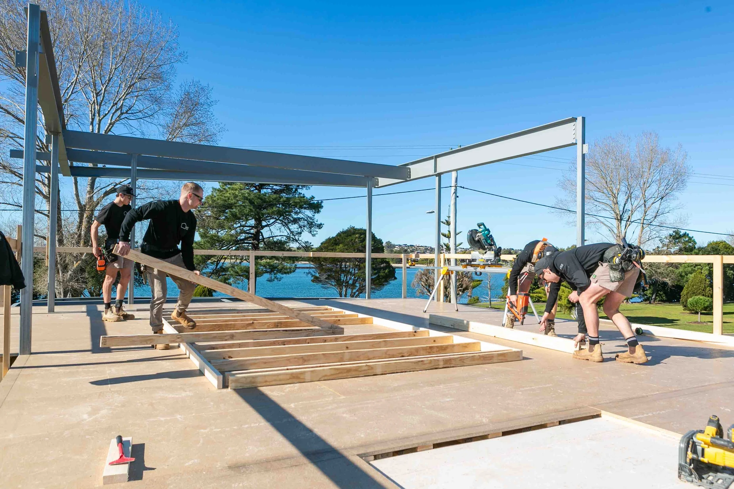 Builders assembling a wooden frame on the second floor of a townhouse.