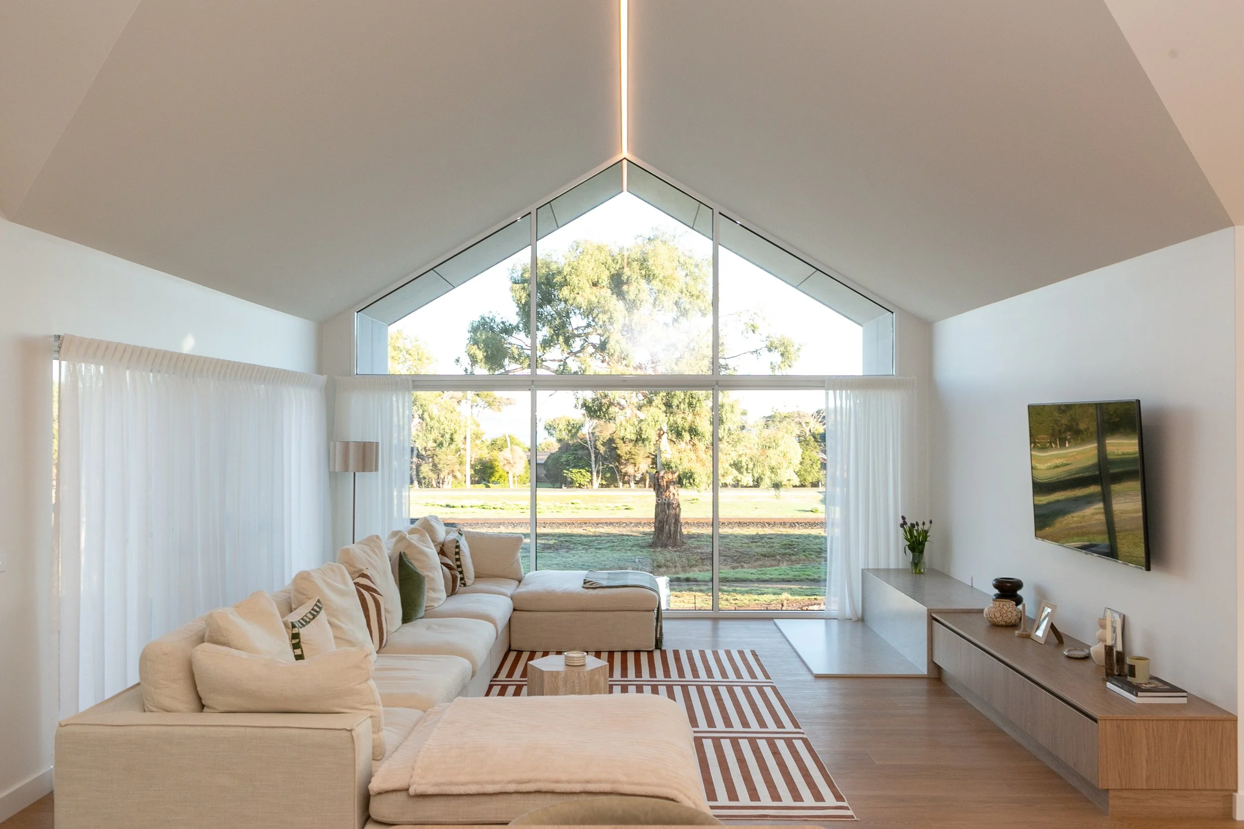 Spacious living room with couch, striped mat and views of a tree.