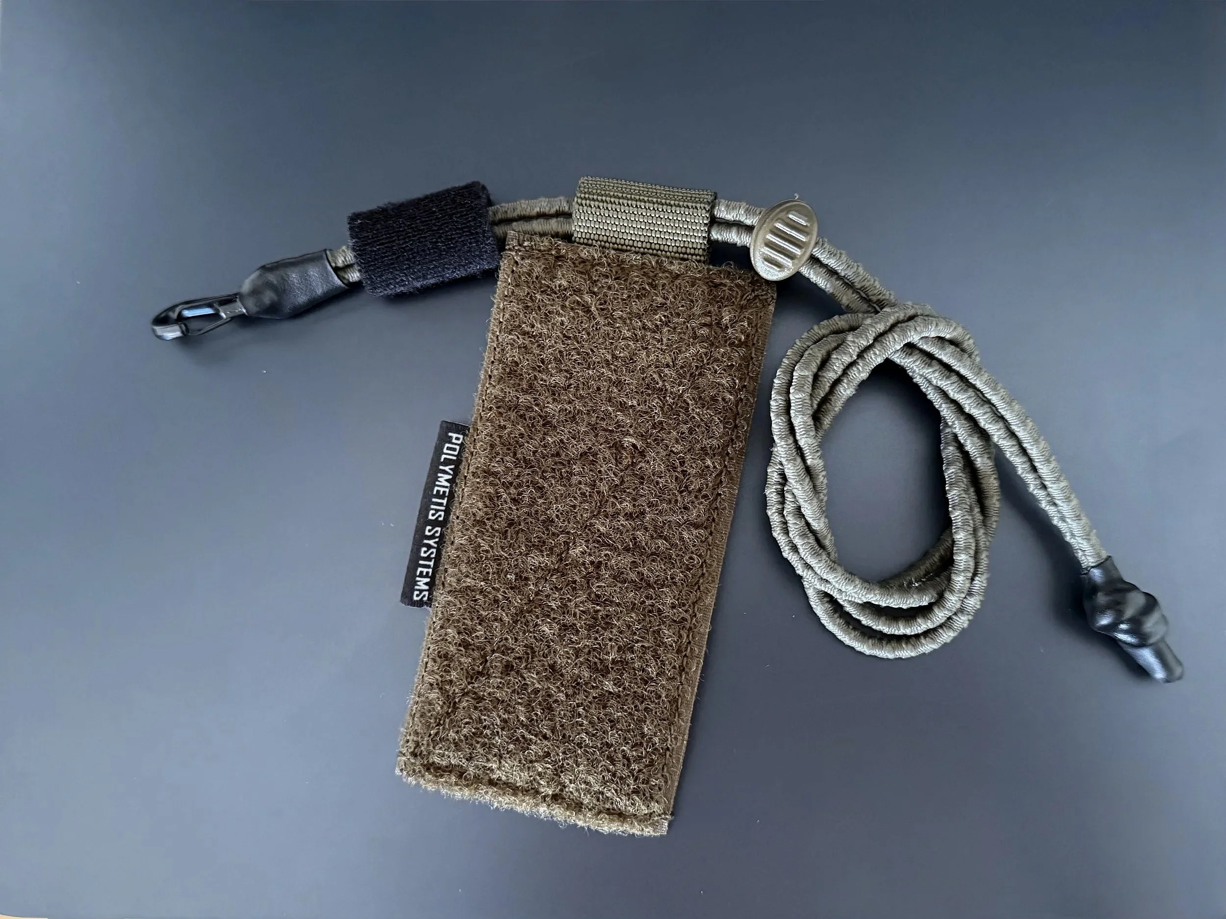 Essential Item Retention Panel EIRP from Polymetis Systems in Ranger Green. To lanyard any mission-critical equipment with metal karabiner and elastic shock cord on an Velcro Panel