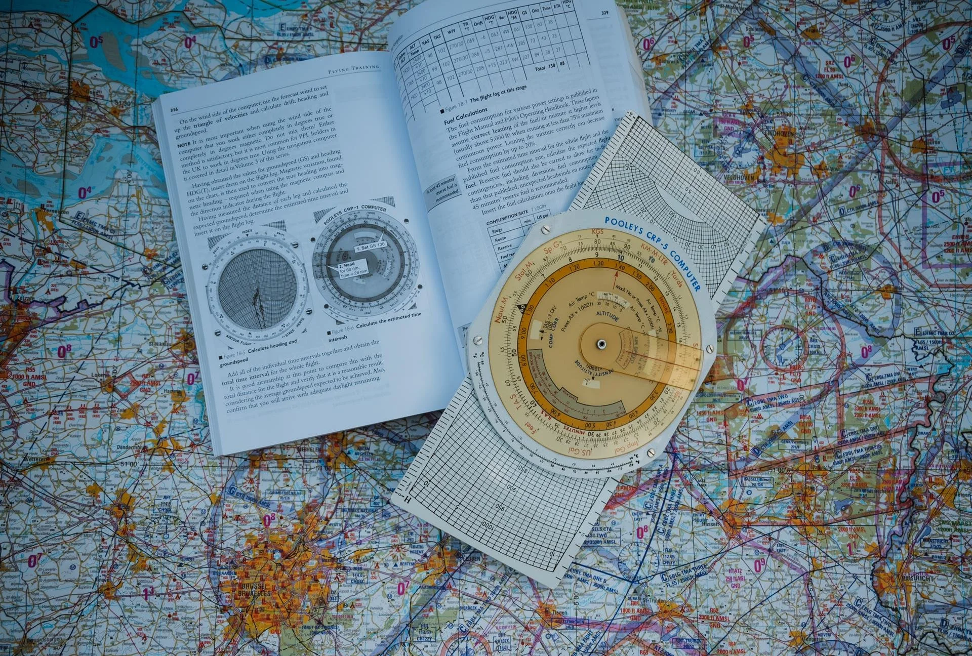 Vliegtuin kaarten, navigatie instrumenten en een boek met trainingsinformatie op een grote kaart.