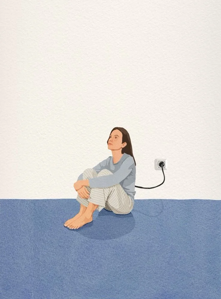Une femme assise par terre, contre un mur blanc, connectée à une prise électrique qui n'est pas utilisée.
