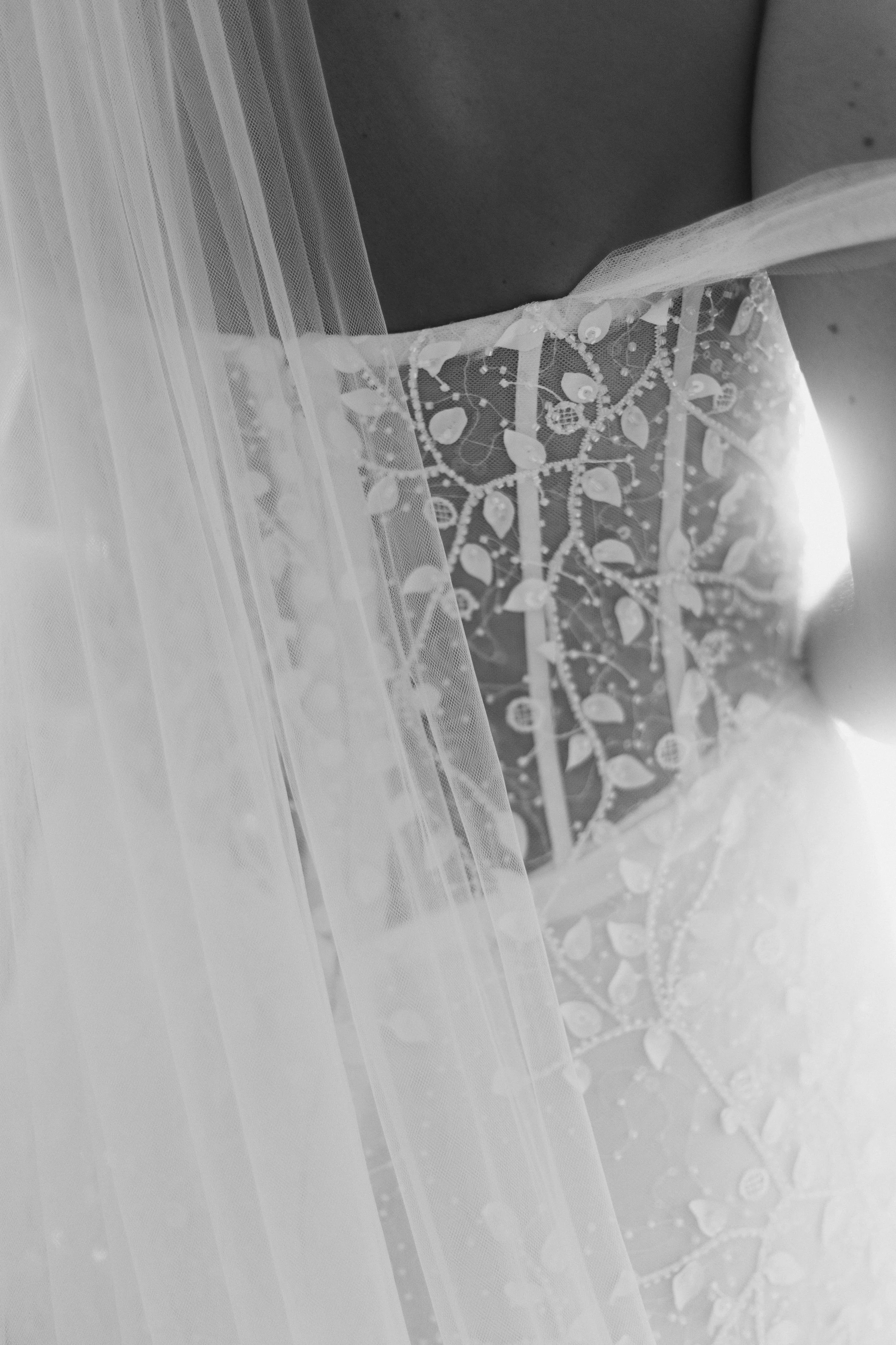 Détail d'une robe de mariée en dentelle avec voile transparent.
