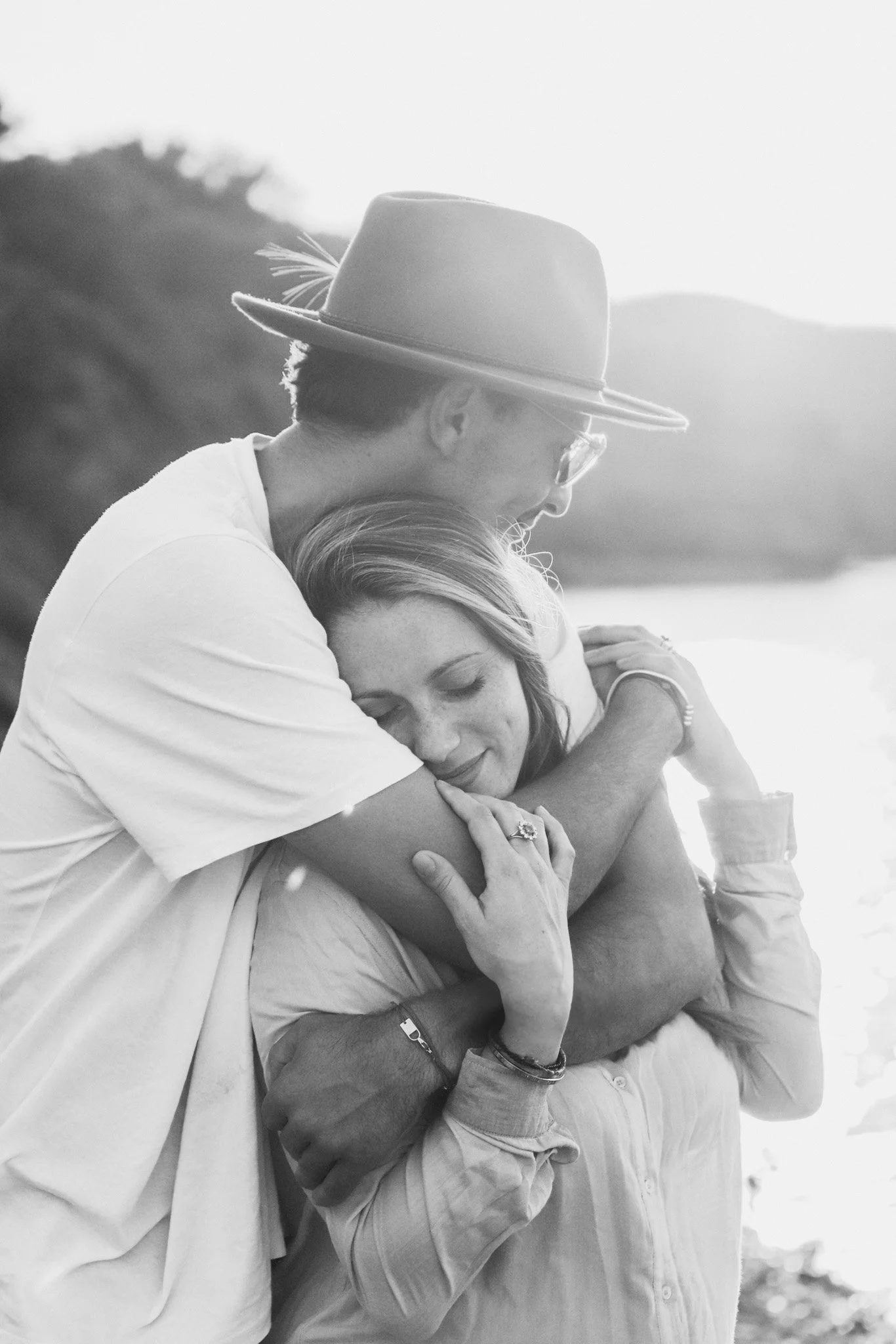 Deux personnes en train de s'étreindre avec un paysage naturel en arrière-plan.