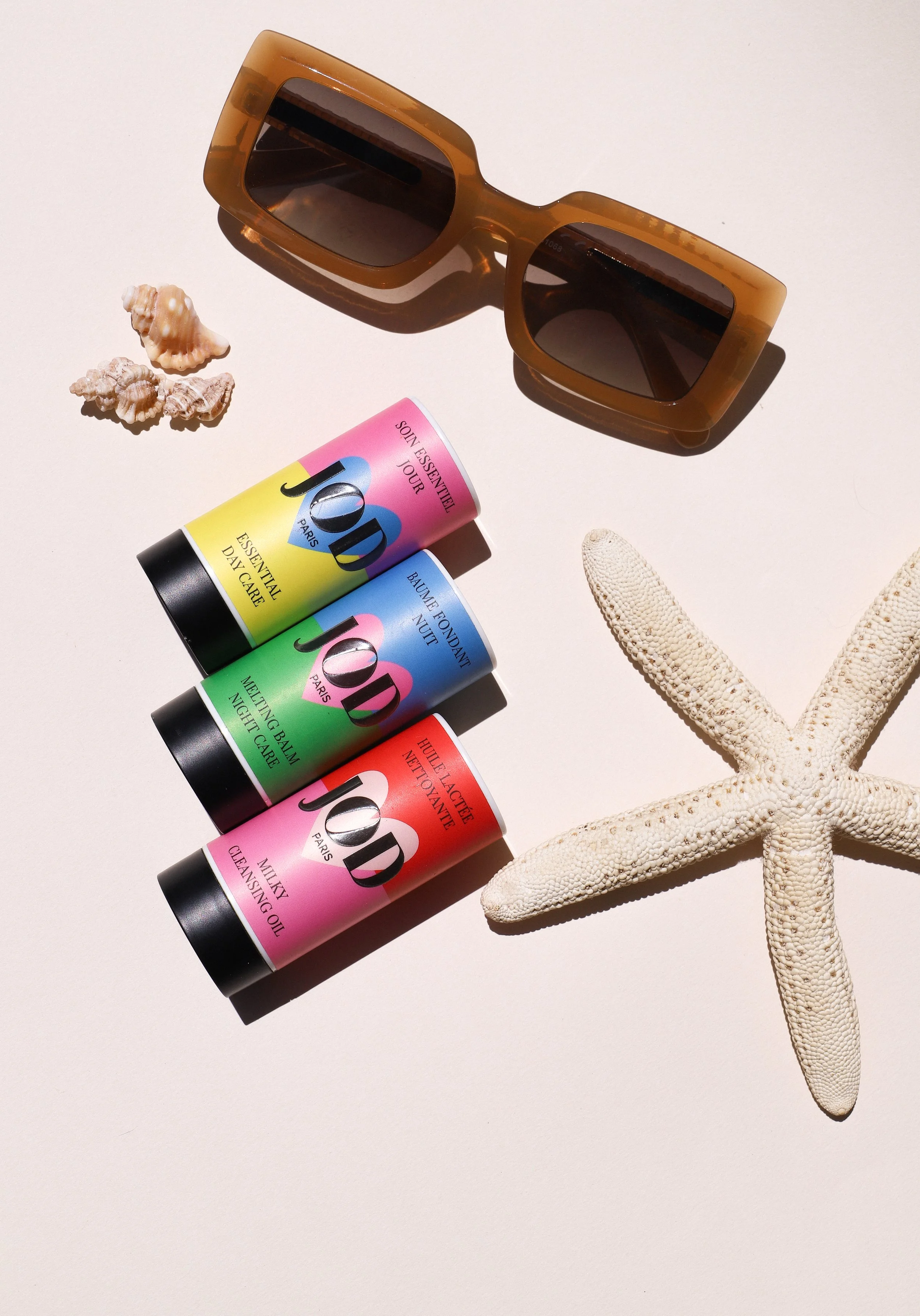 Lunettes de soleil, coquillages, étoile de mer, crèmes de soin de la marque JOD, lunettes de soleil en écaille, étoile de mer blanche.