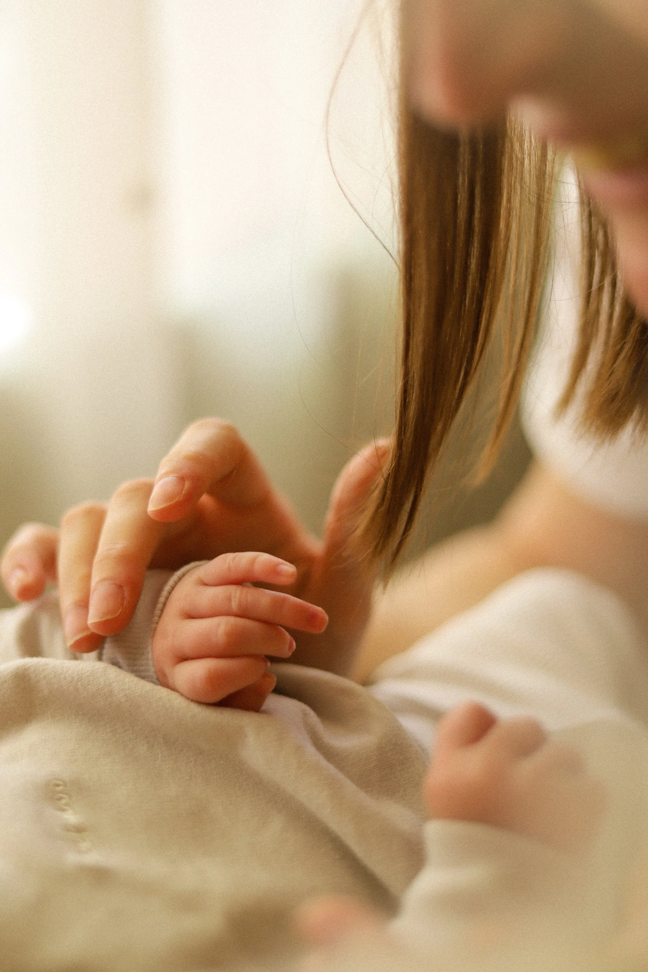 Premier plan d'une mère tenant la main de son bébé.