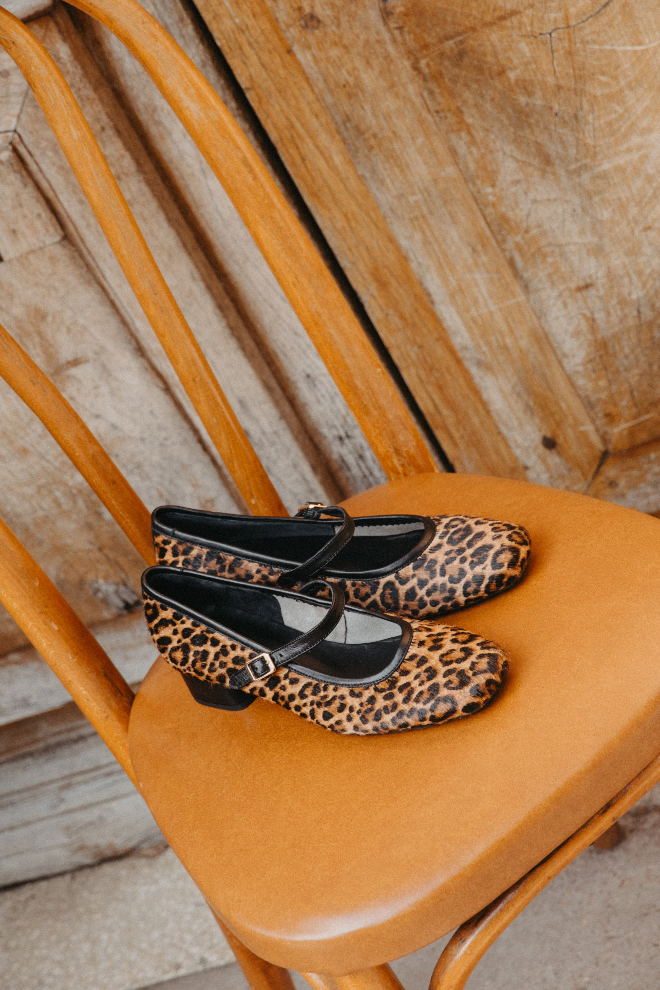 Chaussures à talons avec imprimé léopard sur une chaise en bois orange.