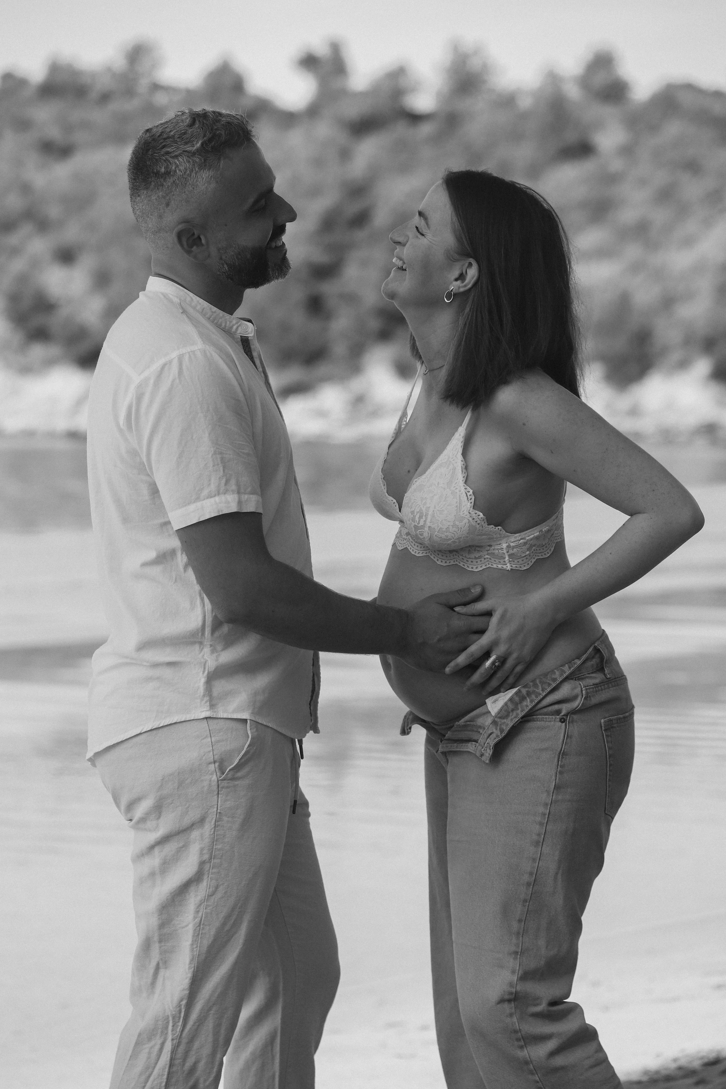 Un couple partage un moment heureux à la plage, elle est enceinte.