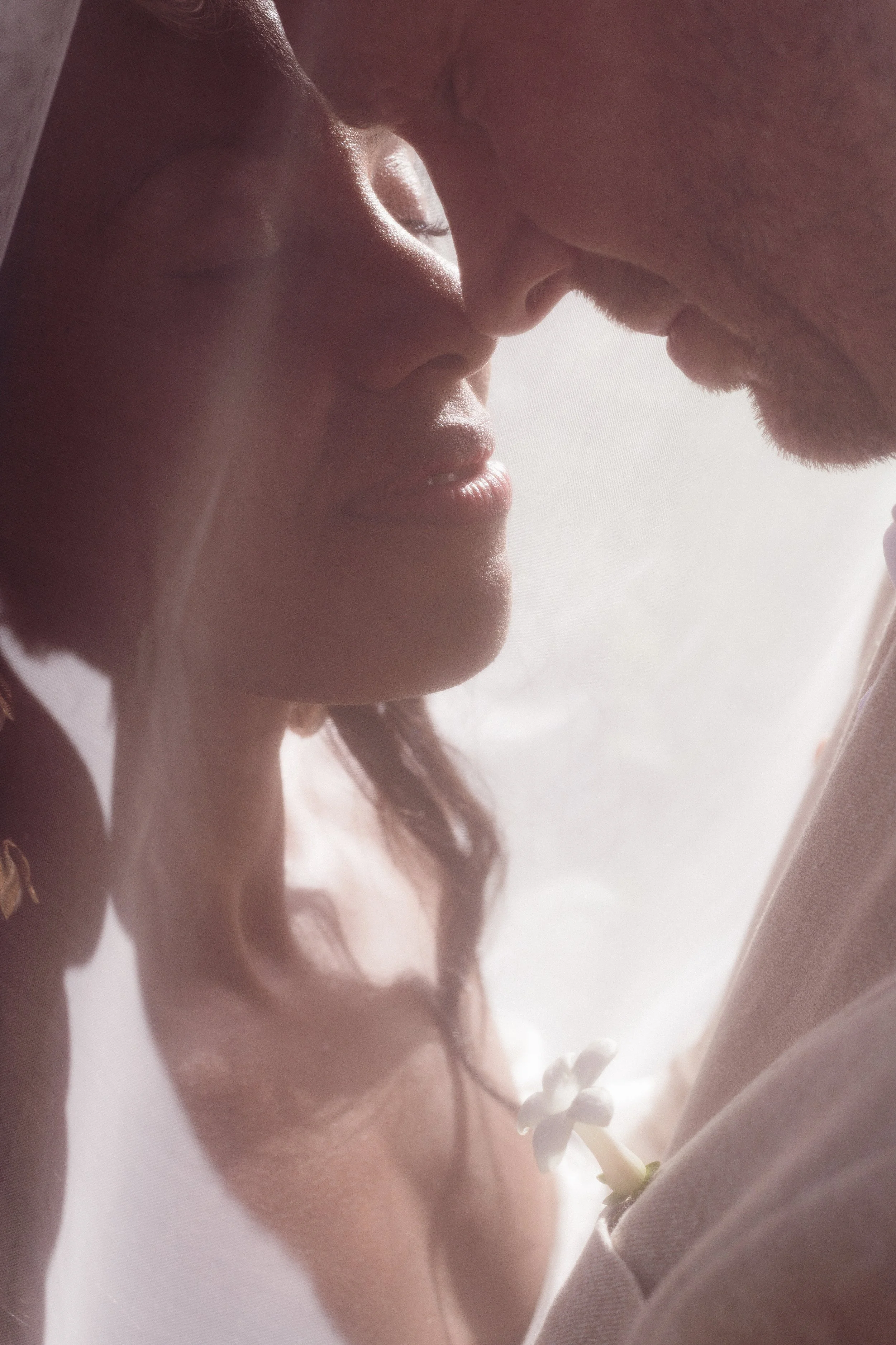 Un couple en contact intime, leur front et leur nez se touchant, en gros plan avec lumière douce