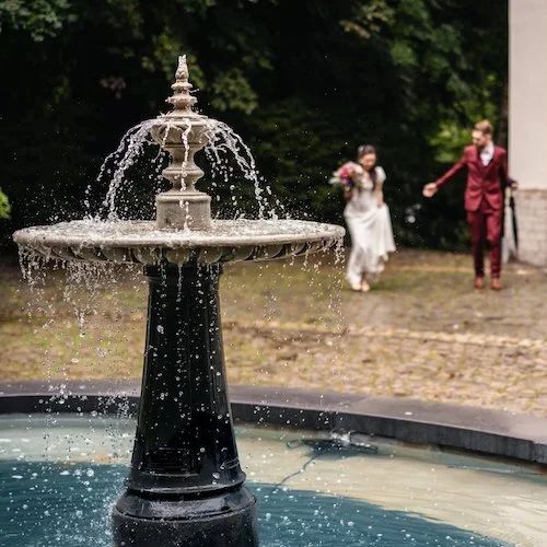 Mariés courant vers une fontaine dans un parc — formule La Belle Aventure — À Tantôt Productions