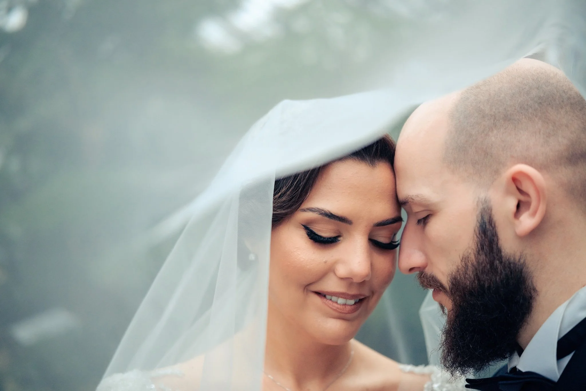 Mariée sous son voile, front contre front avec son mari, portrait de couple intime lors d'un reportage de mariage