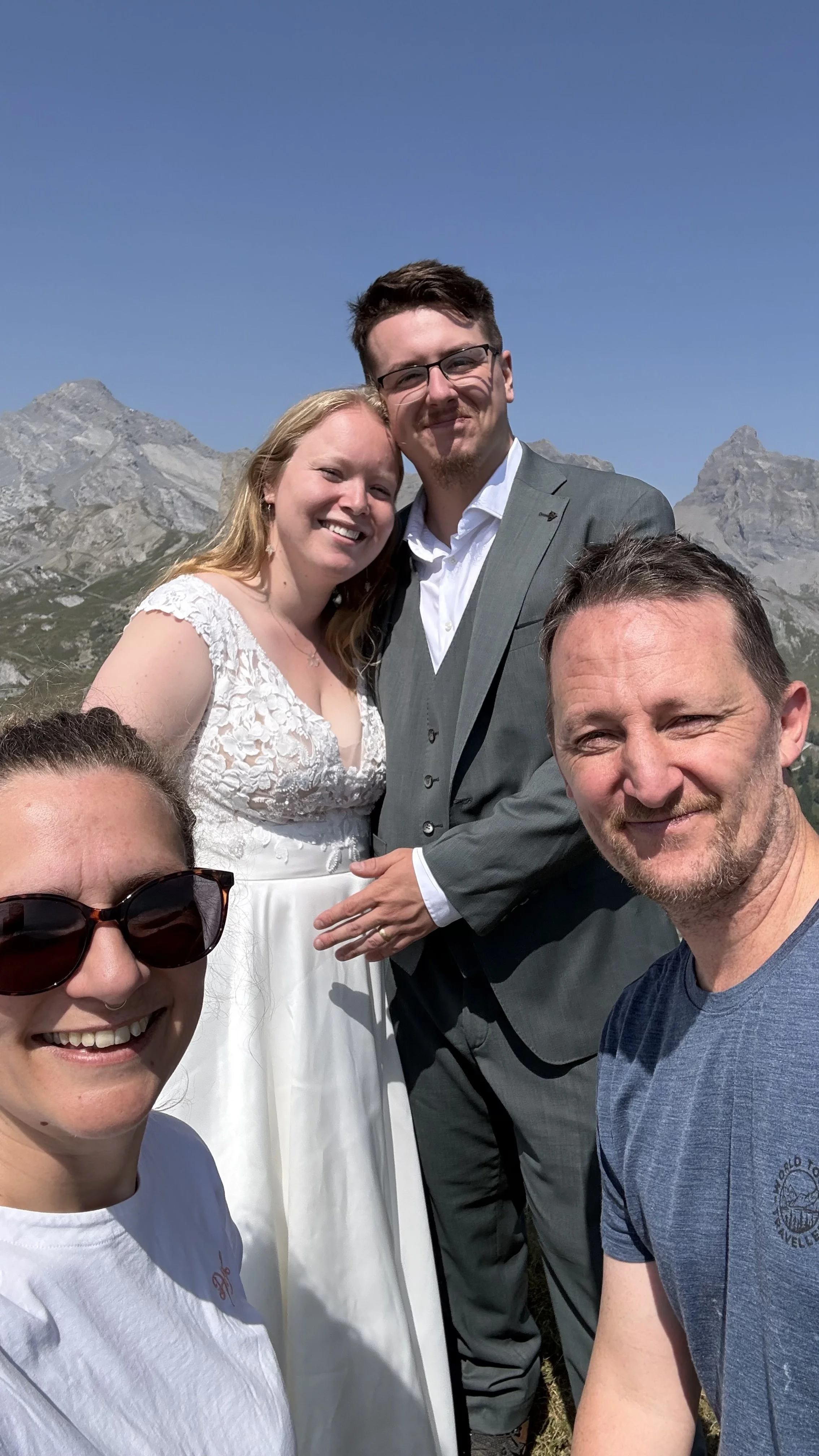 Selfie de groupe avec des mariés devant les sommets rocheux, par grand beau temps – mariage en montagne