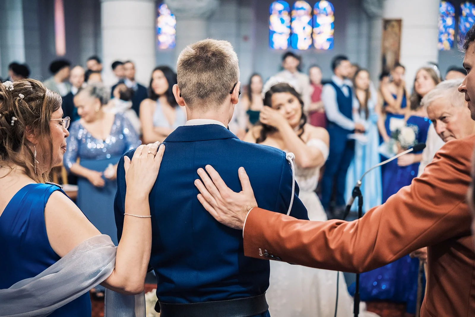 Proches du marié émus pendant la cérémonie religieuse, mains posées sur ses épaules, mariage en Belgique