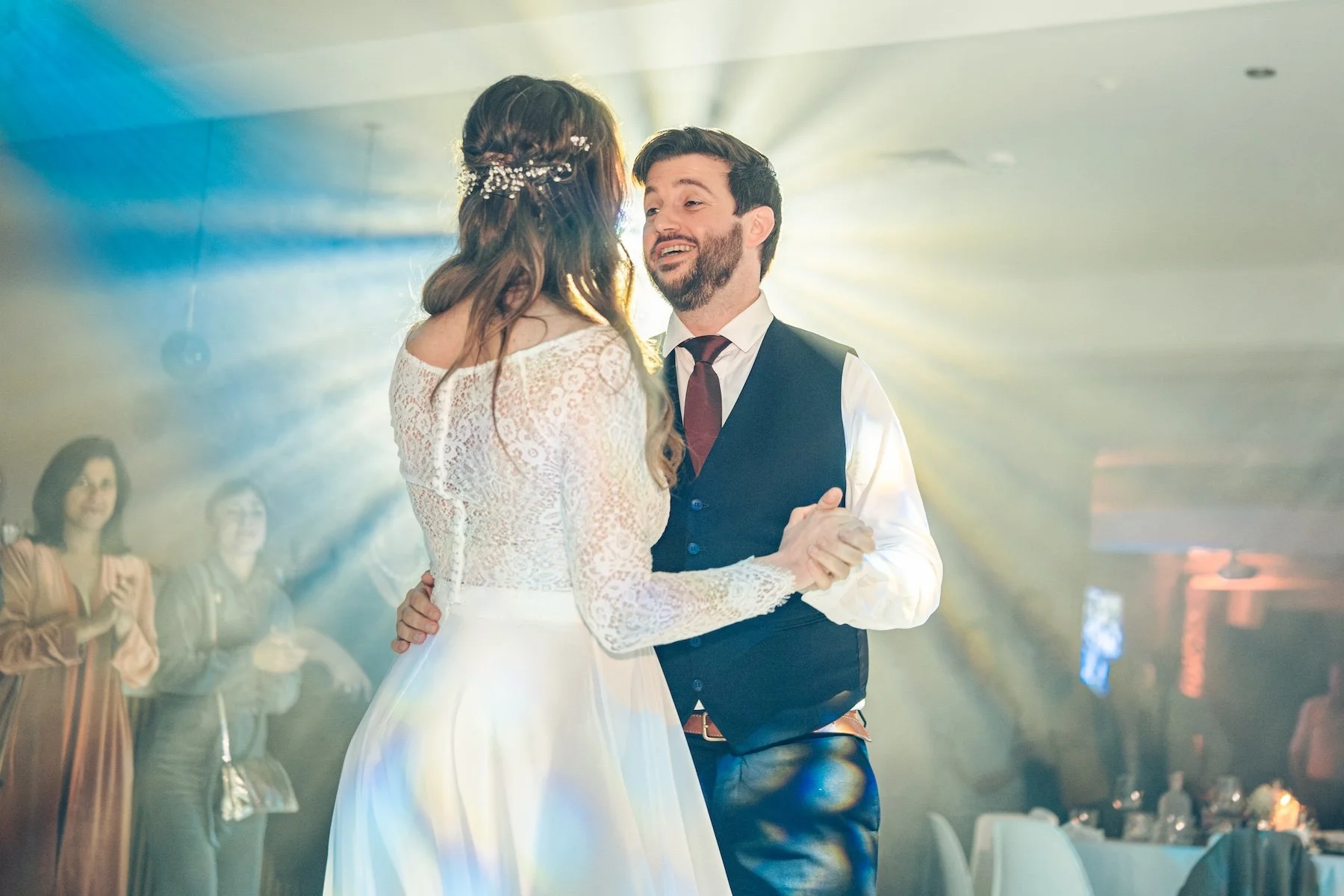 Première danse des mariés en contre-jour, rayons de lumière derrière eux – soirée de mariage en Belgique