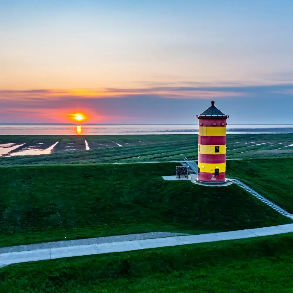 Pilsumer Leuchtturm an der Nordsee bei Sonnenuntergang auf dem Deich