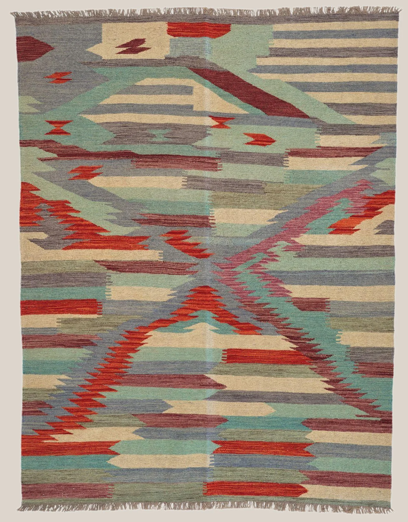 A colorful woven rug with an abstract geometric pattern in shades of green, red, blue, beige, and gray.