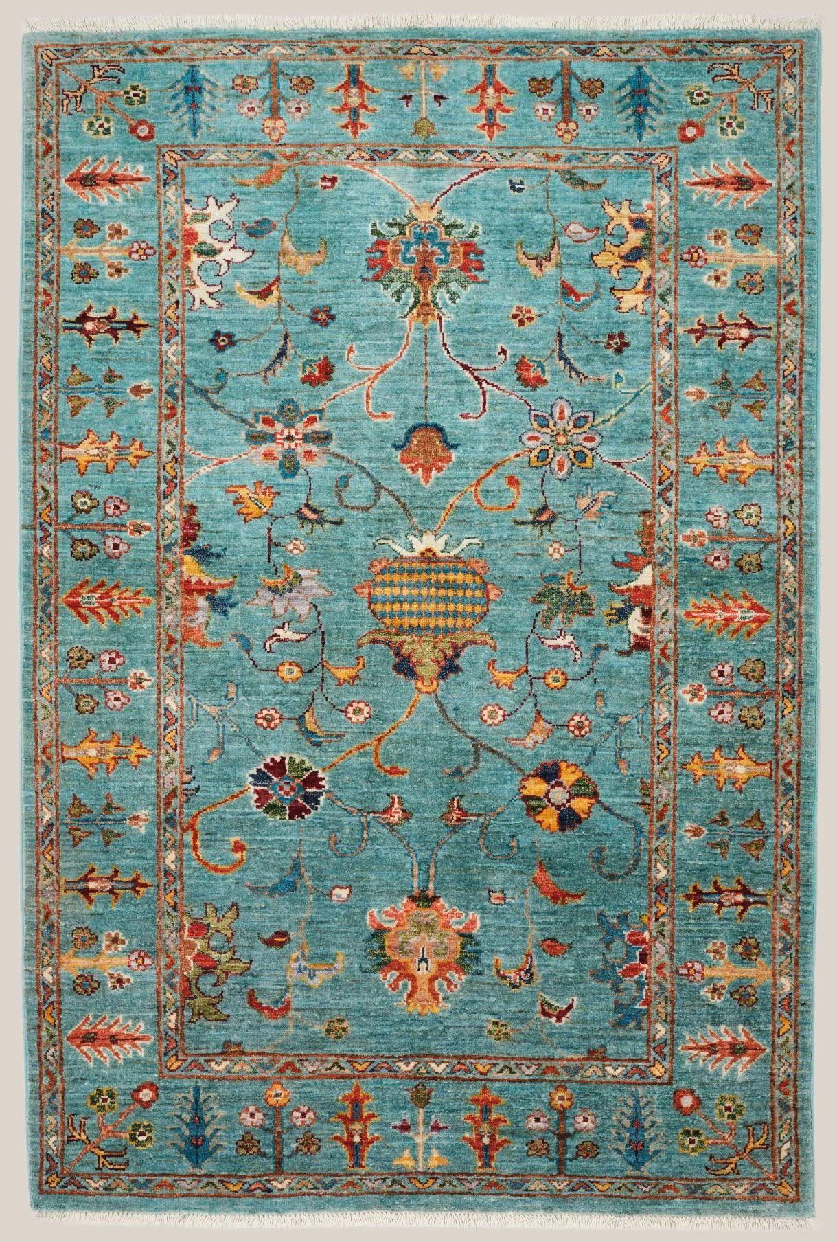 A decorative area rug with a blue background featuring intricate floral and vine patterns in various colors, bordered by a geometric design with floral motifs.